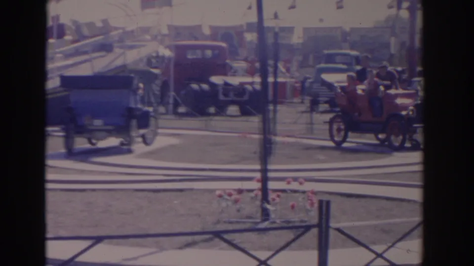 Final frame of the 1962 Florida display shows antique cars, a red truck, a low fence, tents, and spectators in a fairground setting.