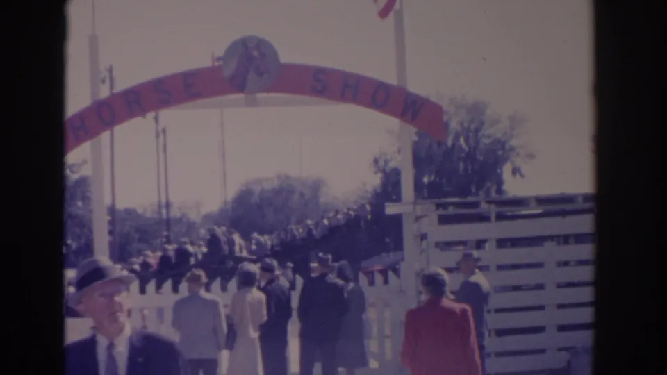 1962 Florida fairgoers walk toward a red HORSE SHOW gateway with white fencing and period clothing visible.