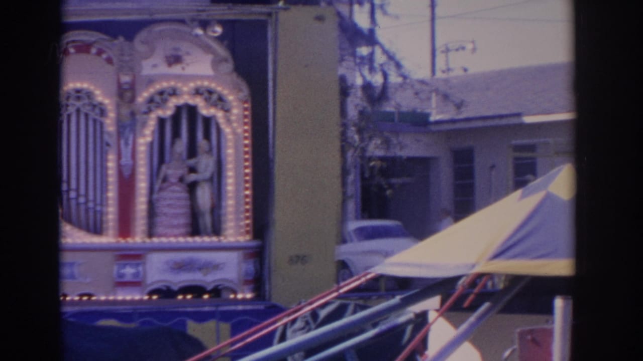 Mechanical organ facade beside striped carnival tenting near a school building.