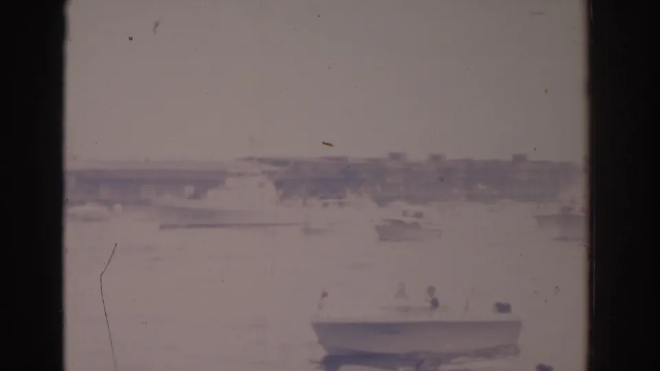 1962 Florida 8mm frame showing small pleasure boats on sunlit harbor water, softened by overexposure and film fade.