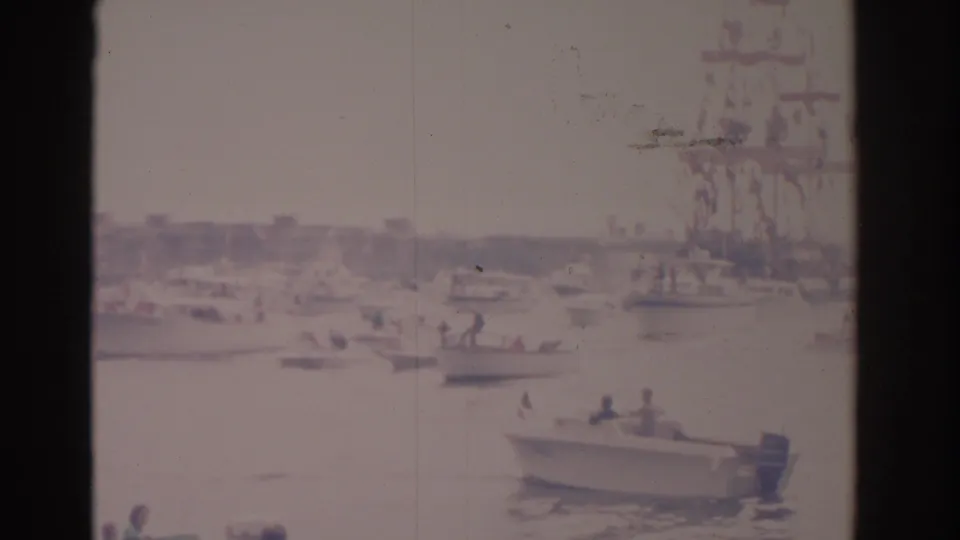 1962 Florida harbor scene with small motorboats near a larger decorated ship, seen through soft, faded 8mm home-movie footage.