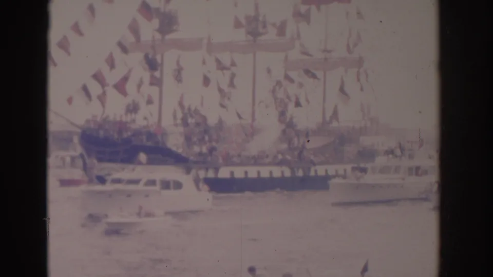 1962 Florida harbor frame showing a tall-masted decorated ship with spectators and small boats around it.