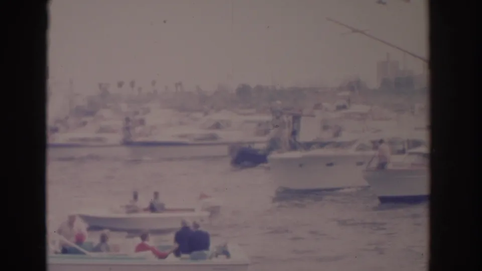 1962 Florida home-movie frame showing small passenger boats crossing a busy marina with larger motorboats behind them.