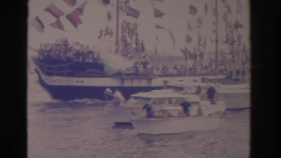 Flag-draped vessel and a smaller cabin boat move through a Florida nautical parade in faded 8mm color.