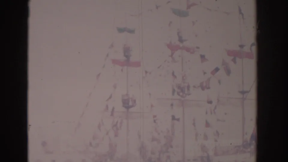 1962 Florida 8mm frame showing a distant decorated ship with red, white, and blue flags and faint waterfront activity.