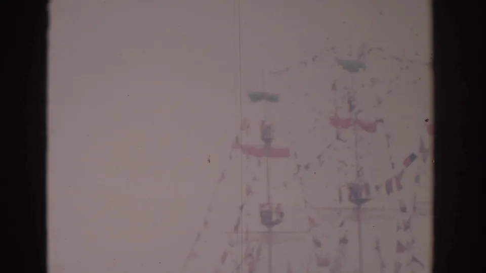 Faded 1962 Florida home-movie frame with a flag-decorated ship, rigging, and indistinct people near the waterfront.