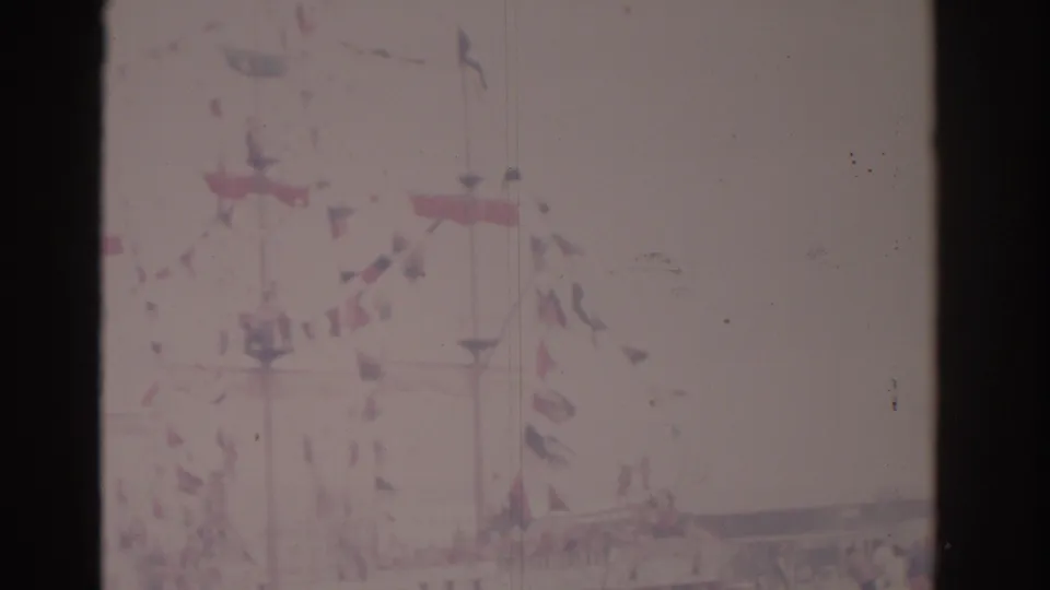 Faded 1962 Florida frame with a decorated ship, strings of flags, small boats, and distant waterfront structures.