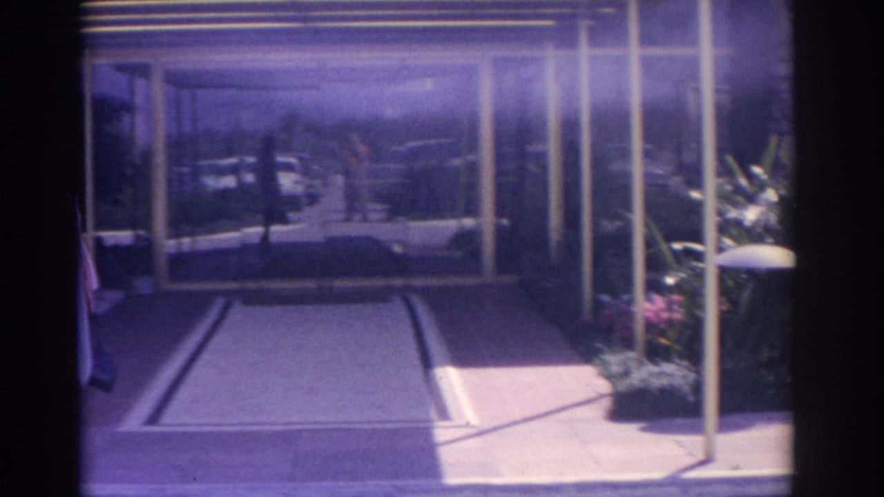 Glass entrance and covered walkway with the woman partly visible at the edge.