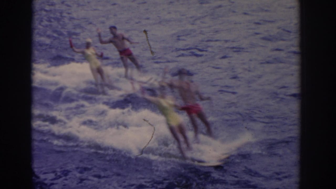 Four adult water skiers move across choppy water with spray around their skis.