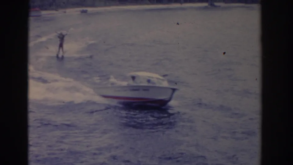 1962 Florida 8mm frame showing the speedboat larger in view, with a water skier following across the lake.