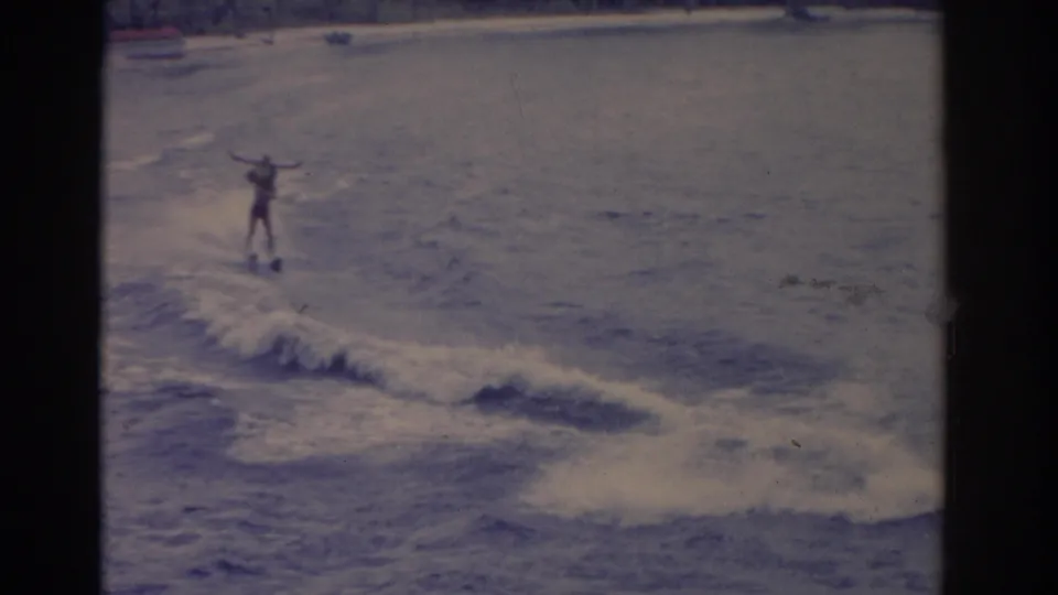 1962 Florida home-movie frame showing a water skier balancing over a foamy wake on the lake.