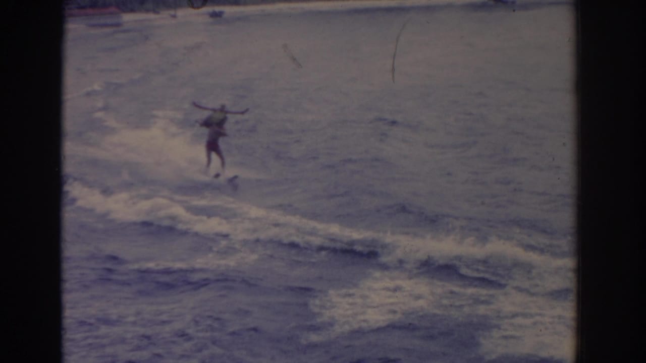 Distant water skier gliding across choppy water with arms outstretched.