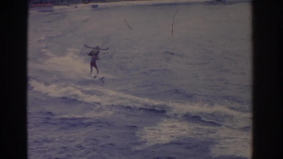 1962 Florida 8mm frame showing a distant water skier balancing across a wake on open water.