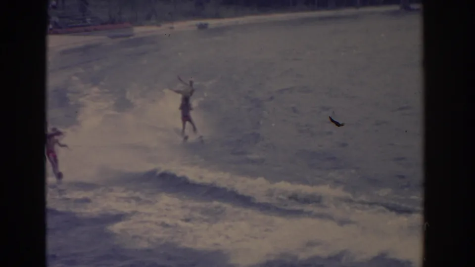 1962 Florida 8mm frame showing a skier upright in choppy wake, with another skier partly visible at left.