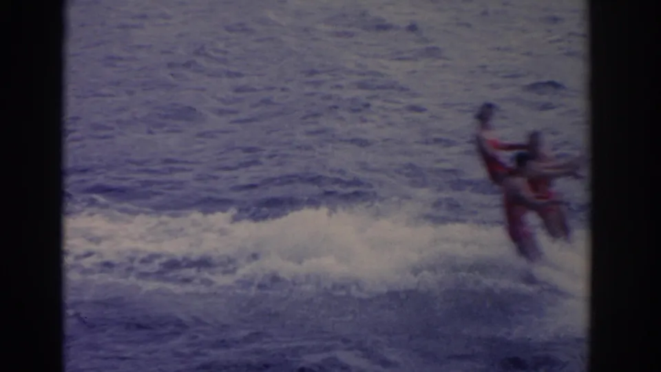A 1962 Florida 8mm frame catches three waterskiers near the right edge, with open water and a bright spray trail behind them.