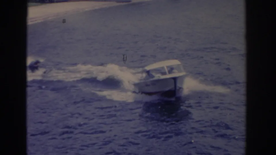 1962 Florida 8mm frame showing a white motorboat crossing choppy water with shoreline in the distance.
