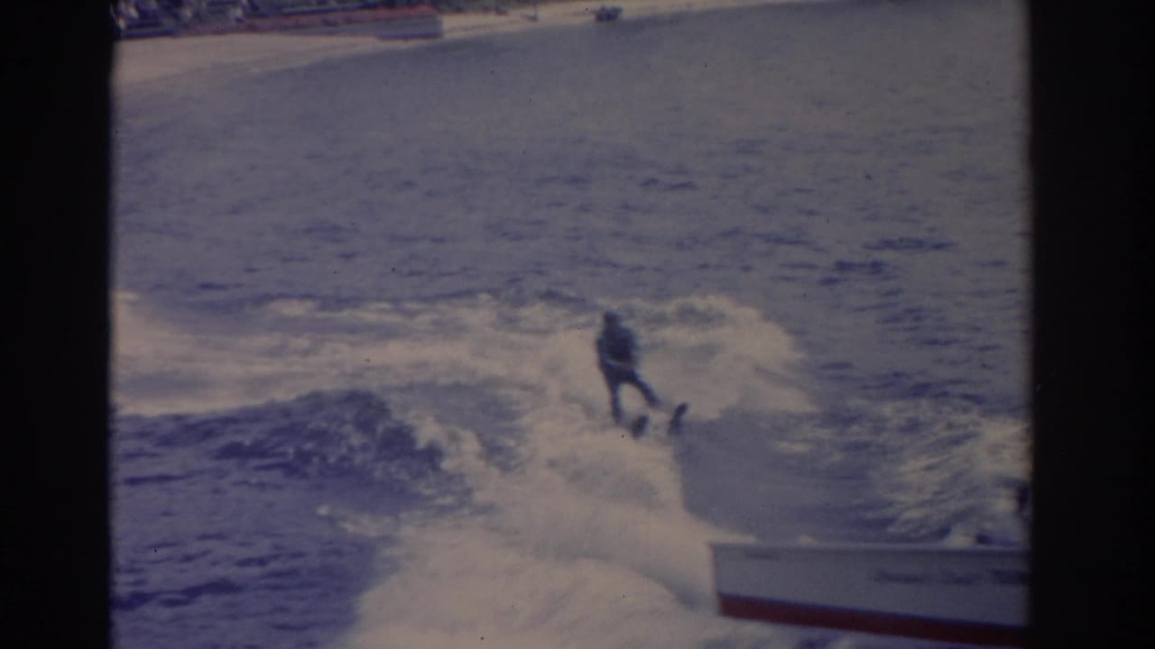 1962 Florida home-movie frame with a water skier riding behind a motorboat amid heavy spray.