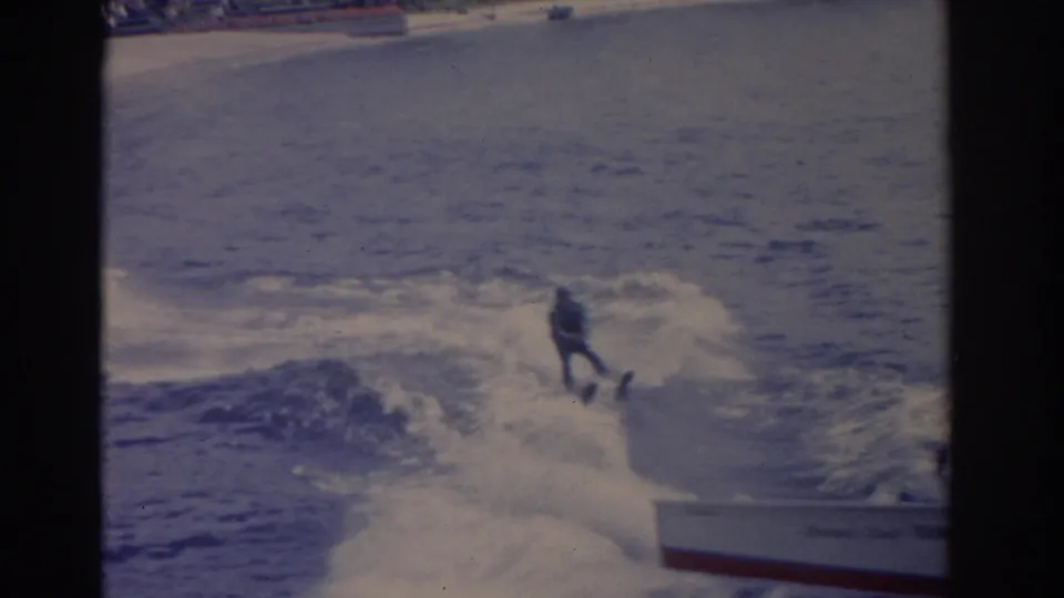 1962 Florida home-movie frame with a water skier riding behind a motorboat amid heavy spray.