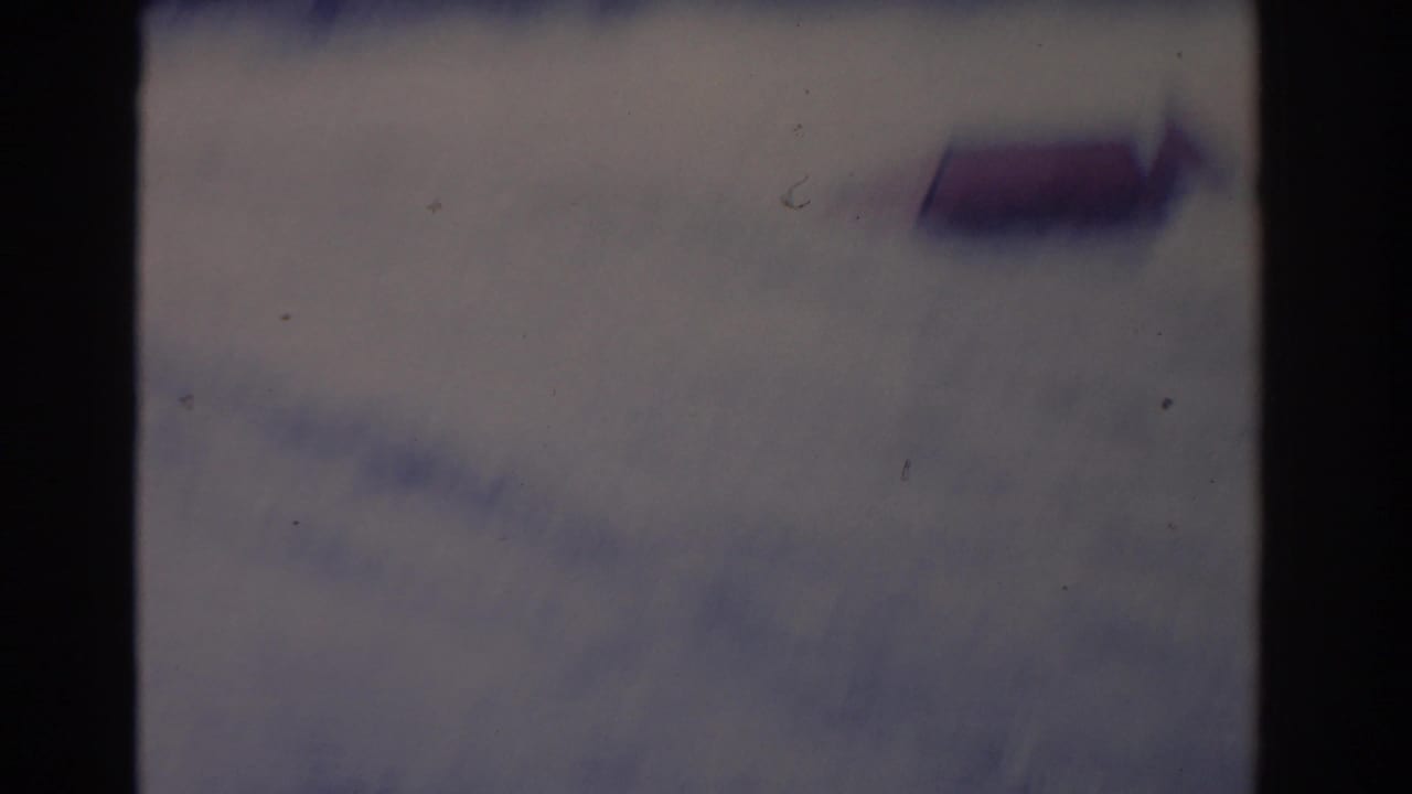 Soft-focused 8mm frame from the Florida water-ski sequence, with water blur and the red ramp faintly visible.