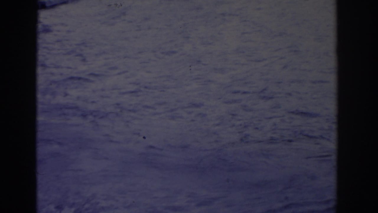 Soft 8mm frame from the 1962 Florida water-ski scene, showing mostly open water, wake texture, and dark frame edges.