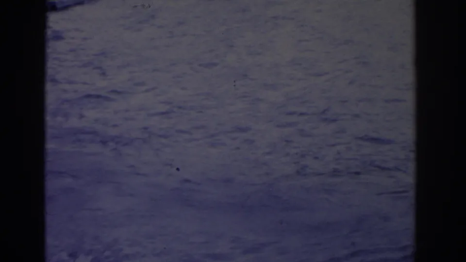 Soft 8mm frame from the 1962 Florida water-ski scene, showing mostly open water, wake texture, and dark frame edges.
