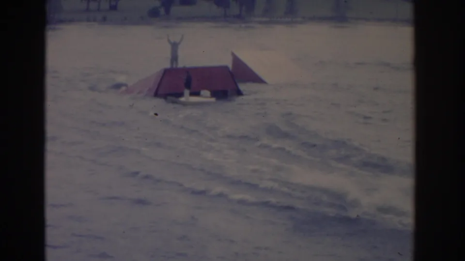 1962 Florida home-movie frame showing a red floating ramp on choppy water with a person standing on it, arms raised.