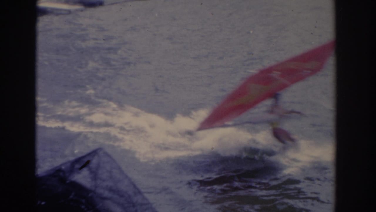 1962 Florida home-movie frame showing the red water sport sail dipping low as spray breaks around the performer.