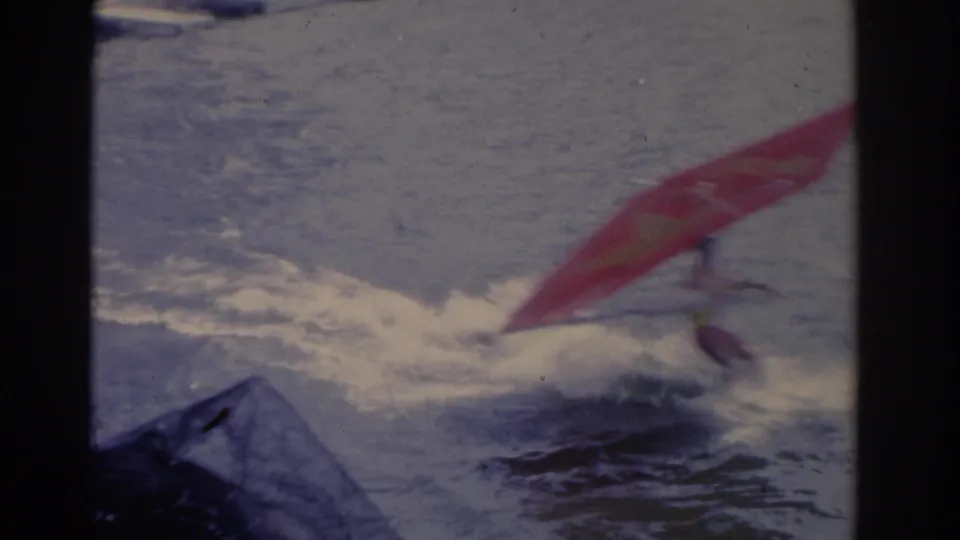 1962 Florida home-movie frame showing the red water sport sail dipping low as spray breaks around the performer.