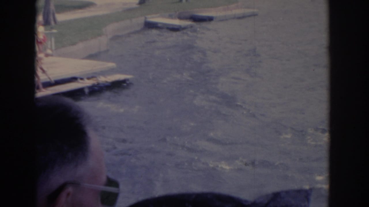 1962 Florida frame showing choppy water near a dock, with a spectator's head and sunglasses entering the foreground.