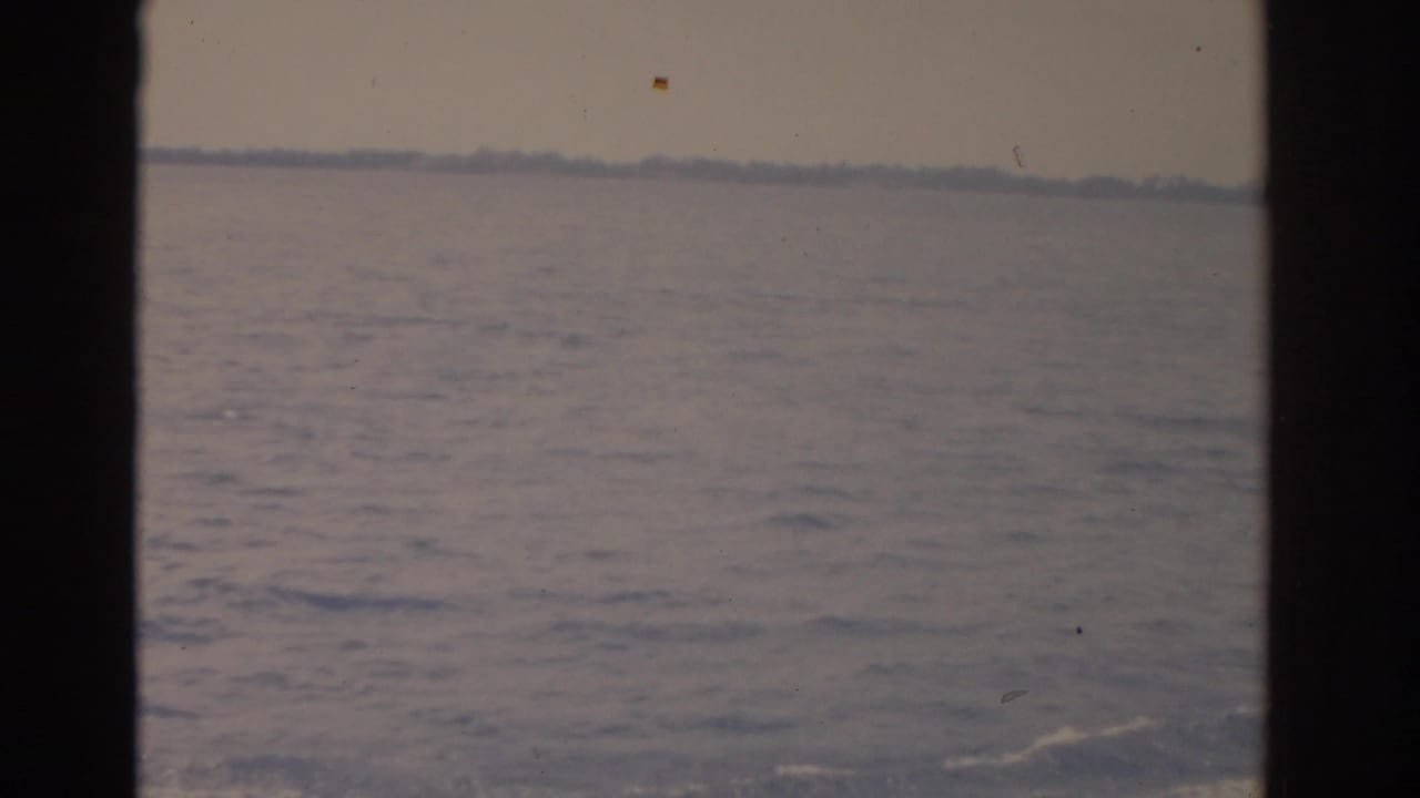 Open lake water with a hazy tree-lined shoreline in the distance.