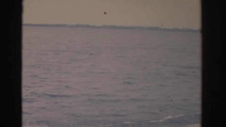 1962 Florida 8mm frame looking across open lake water toward a distant tree-lined shore under a hazy sky.