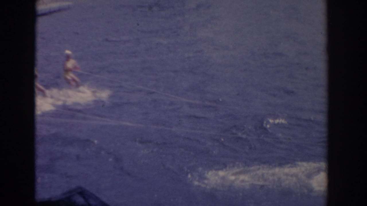 A Florida lake recreation scene shows distant figures moving through blue water, with wake and heavy 8mm borders visible.