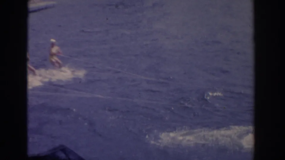 A Florida lake recreation scene shows distant figures moving through blue water, with wake and heavy 8mm borders visible.