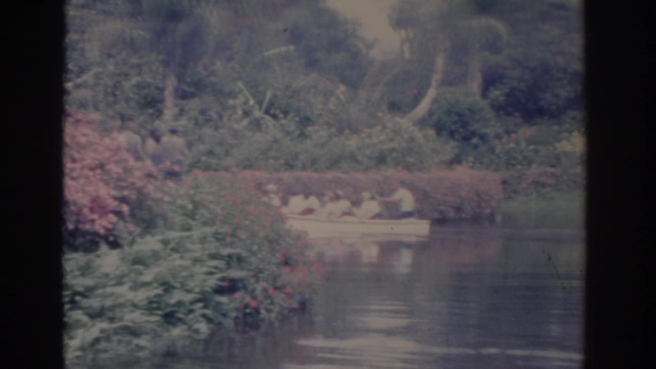 The white boat continues across reflective water in the 1962 Florida home-movie footage, with adults seated low in the hull.