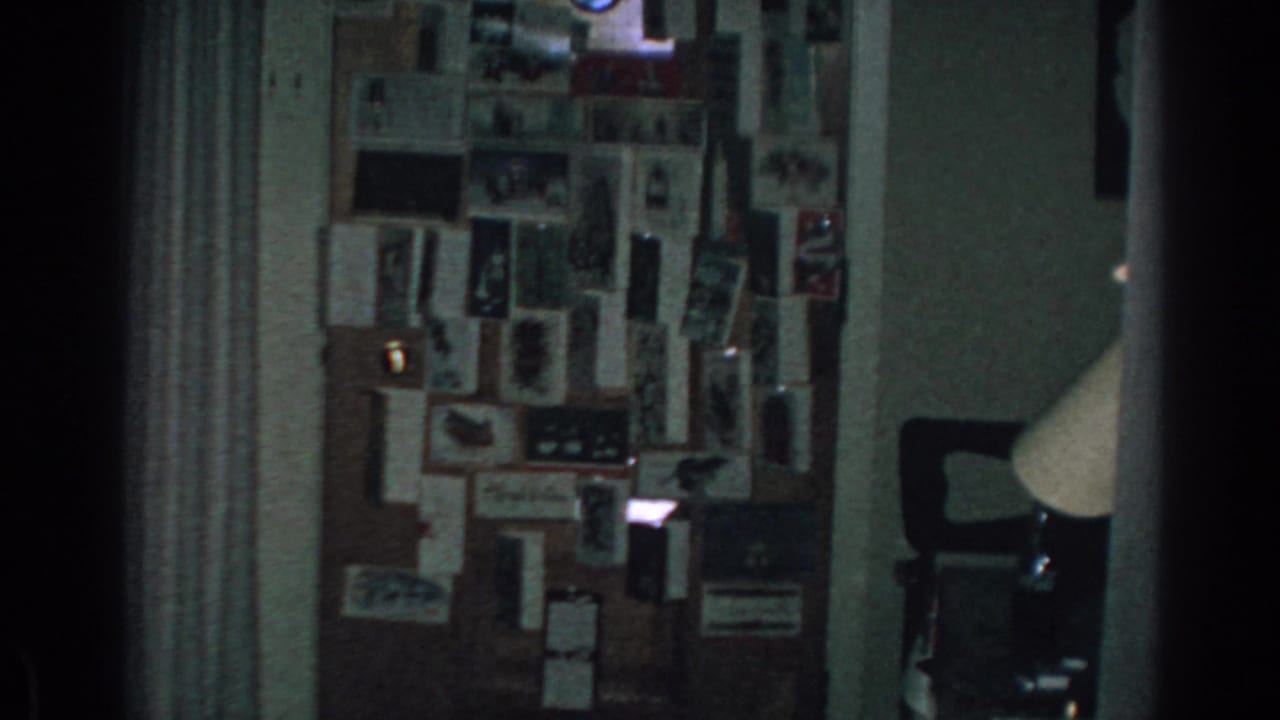 Low-light interior view of a photo collage wall beside a curtain and lamp.