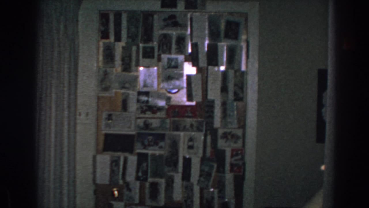 Dim interior wall with a corkboard covered in cards and photographs.