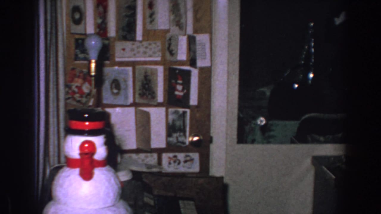 1962 Gary, Indiana interior frame with a snowman decoration before a wall of cards, pictures, and pinned papers.