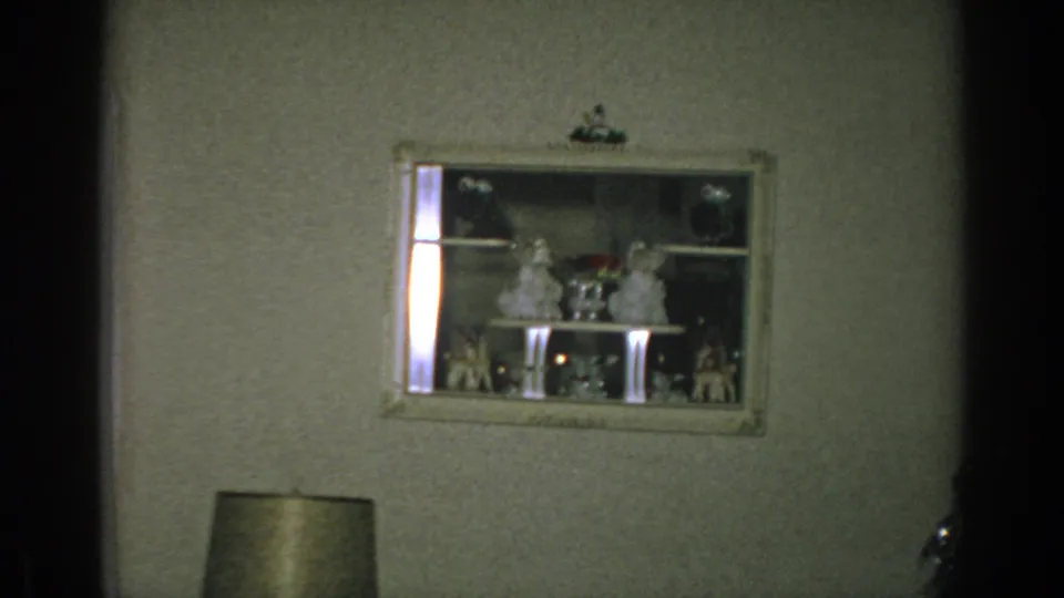 1962 Gary, Indiana interior view of a wall display cabinet holding small holiday figurines above a lamp shade.