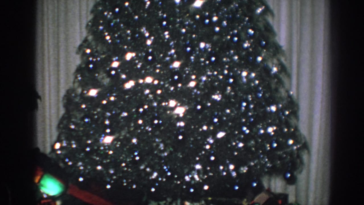 1962 Gary, Indiana 8mm frame with a lit Christmas tree partly divided by a dark vertical camera-edge shadow.