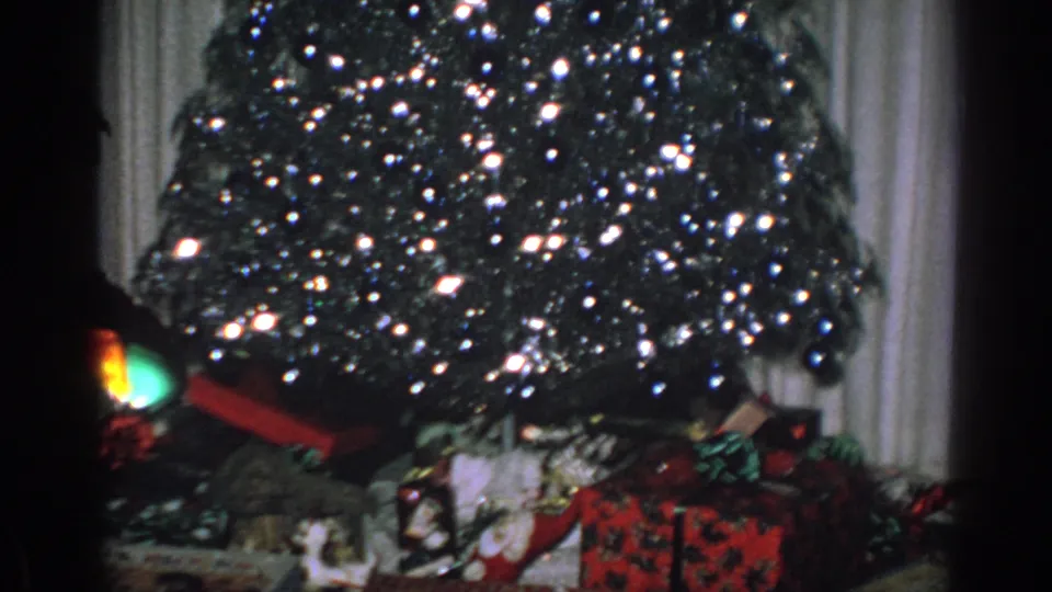 1962 Gary, Indiana 8mm frame showing the lower Christmas tree with wrapped presents and bows beneath it.