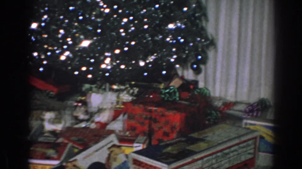 1962 Gary, Indiana 8mm frame showing presents beneath a tinsel-covered Christmas tree indoors.