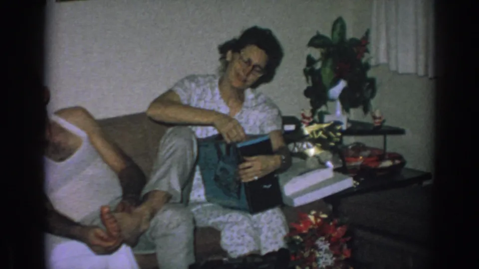 The woman smiles toward the camera while holding the opened gift in the 1962 living-room Christmas Eve scene.