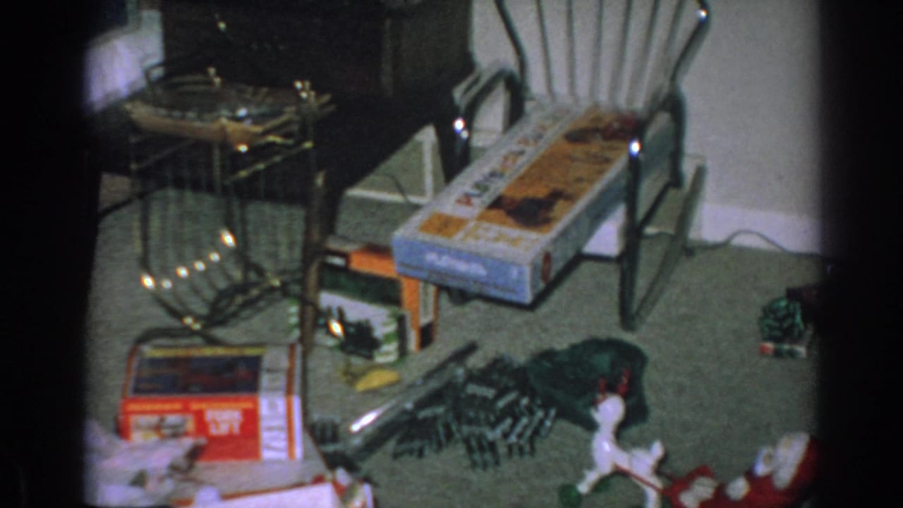 Green carpet with opened boxes, toys, furniture, and a red Santa sleigh decoration.