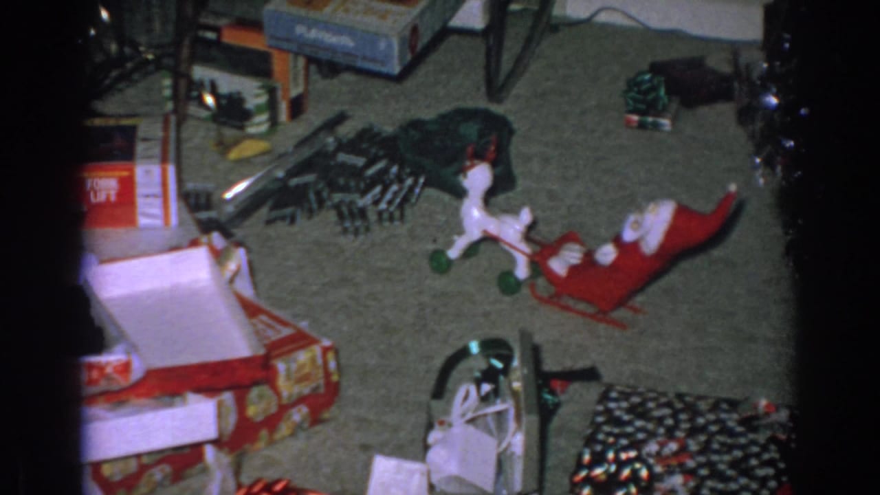 Scattered toy boxes, a white reindeer, a red sleigh, and wrapping on carpet.