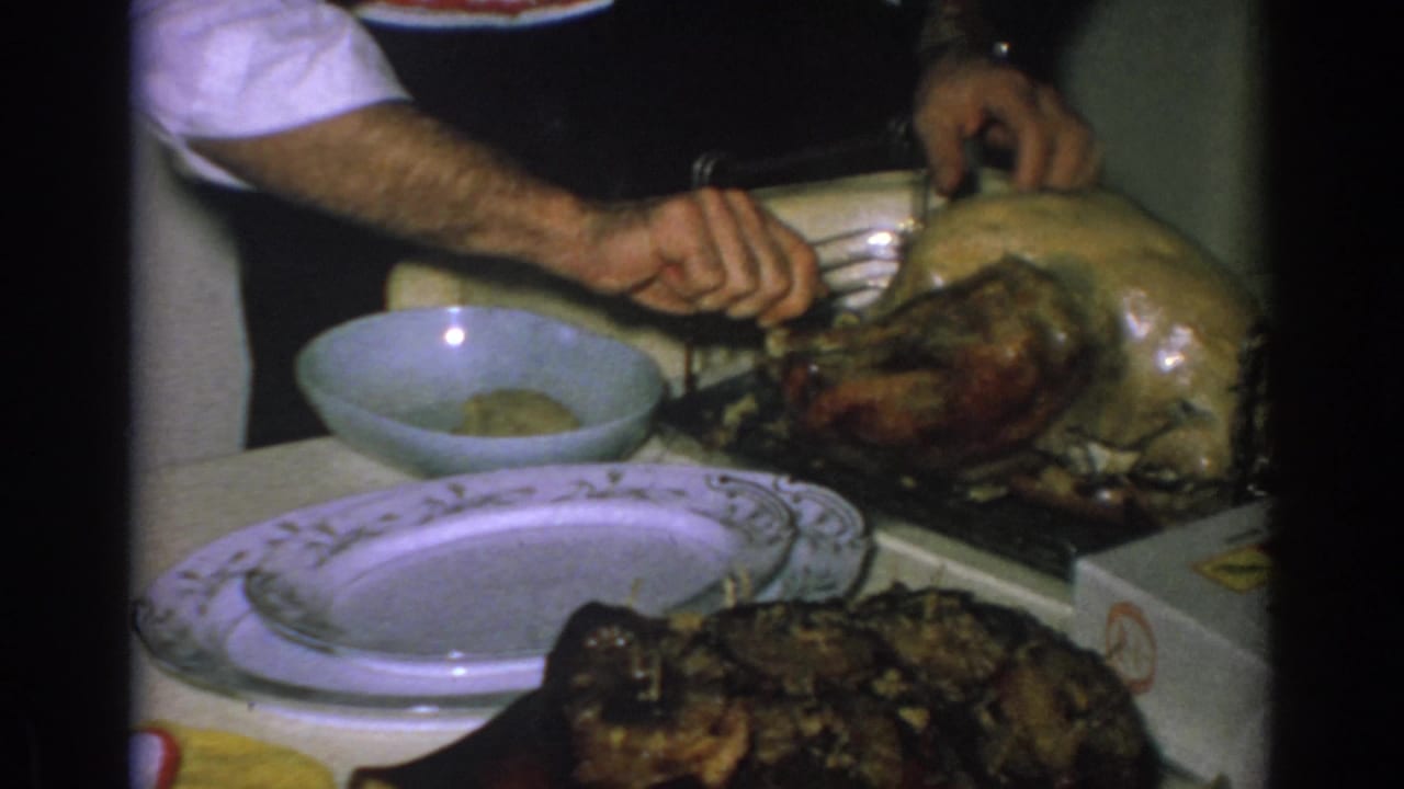 Hands carve a roasted turkey at a kitchen table in the 1962 Gary, Indiana home-movie footage.