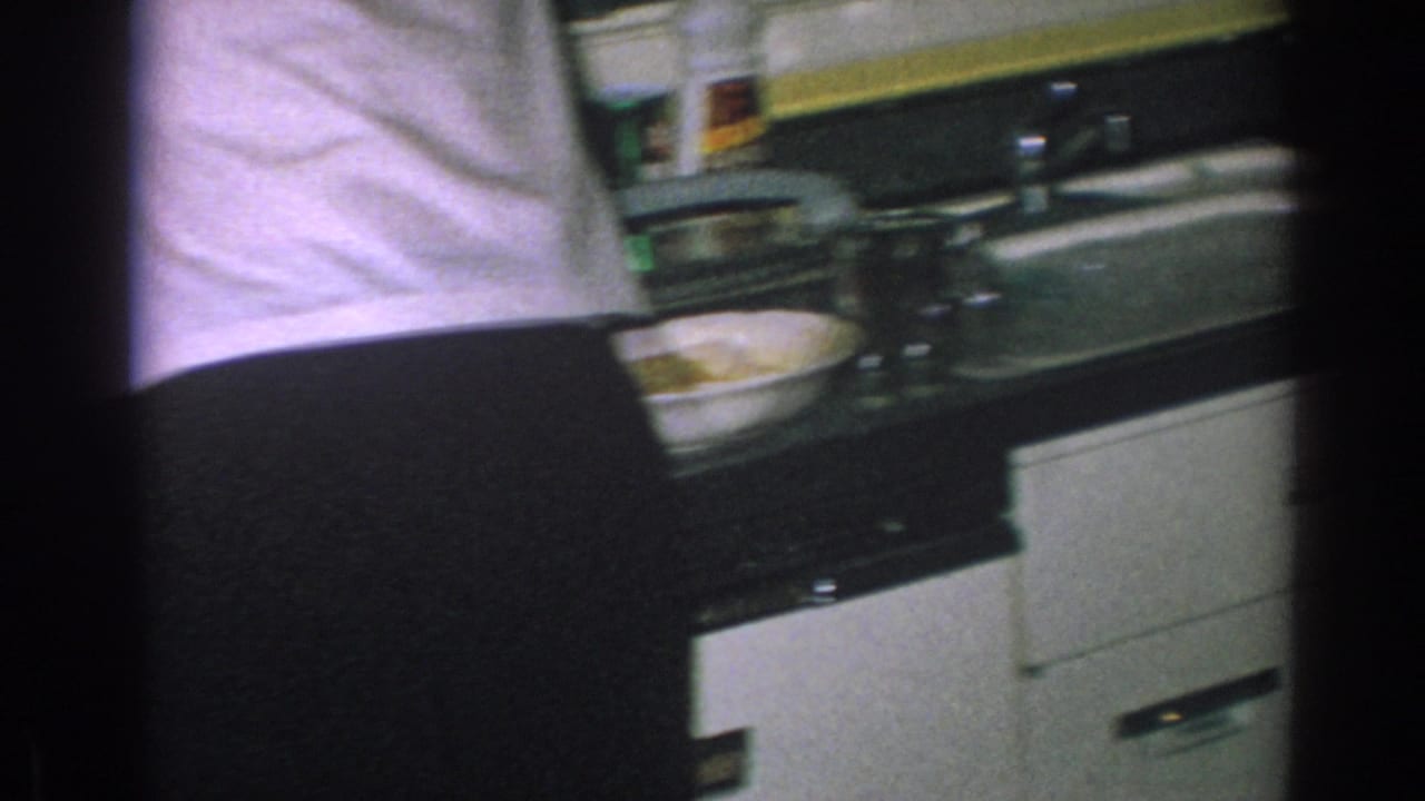 Woman at a kitchen counter beside pots, dishes, and white lower cabinets.