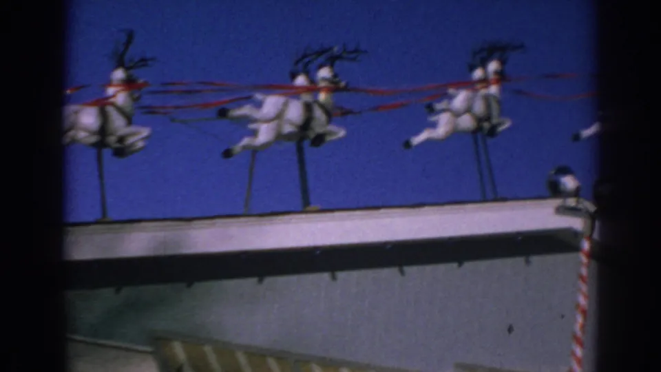 Final 1962 Gary, Indiana frame showing reindeer figures on a rooftop display with a candy-cane striped pole at the edge.
