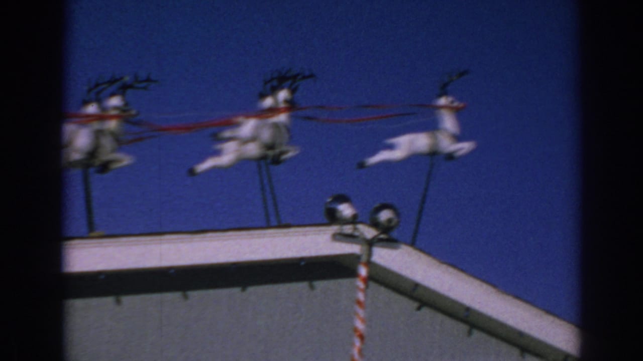Reindeer decoration and striped pole on a roof under a blue sky.
