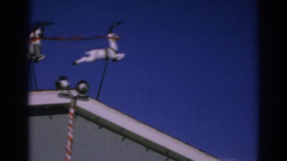 1962 Gary, Indiana home-movie still showing a cropped view of the rooftop reindeer decoration above the roof corner.