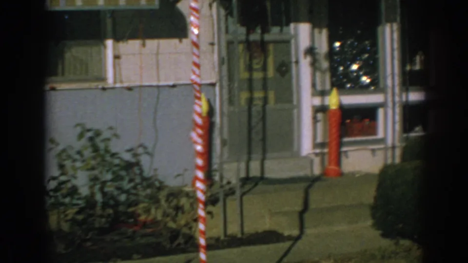 Final frame shows the Gary, Indiana trailer doorway area with a striped holiday pole, red candle decoration, steps, shrubs, and partial window display.